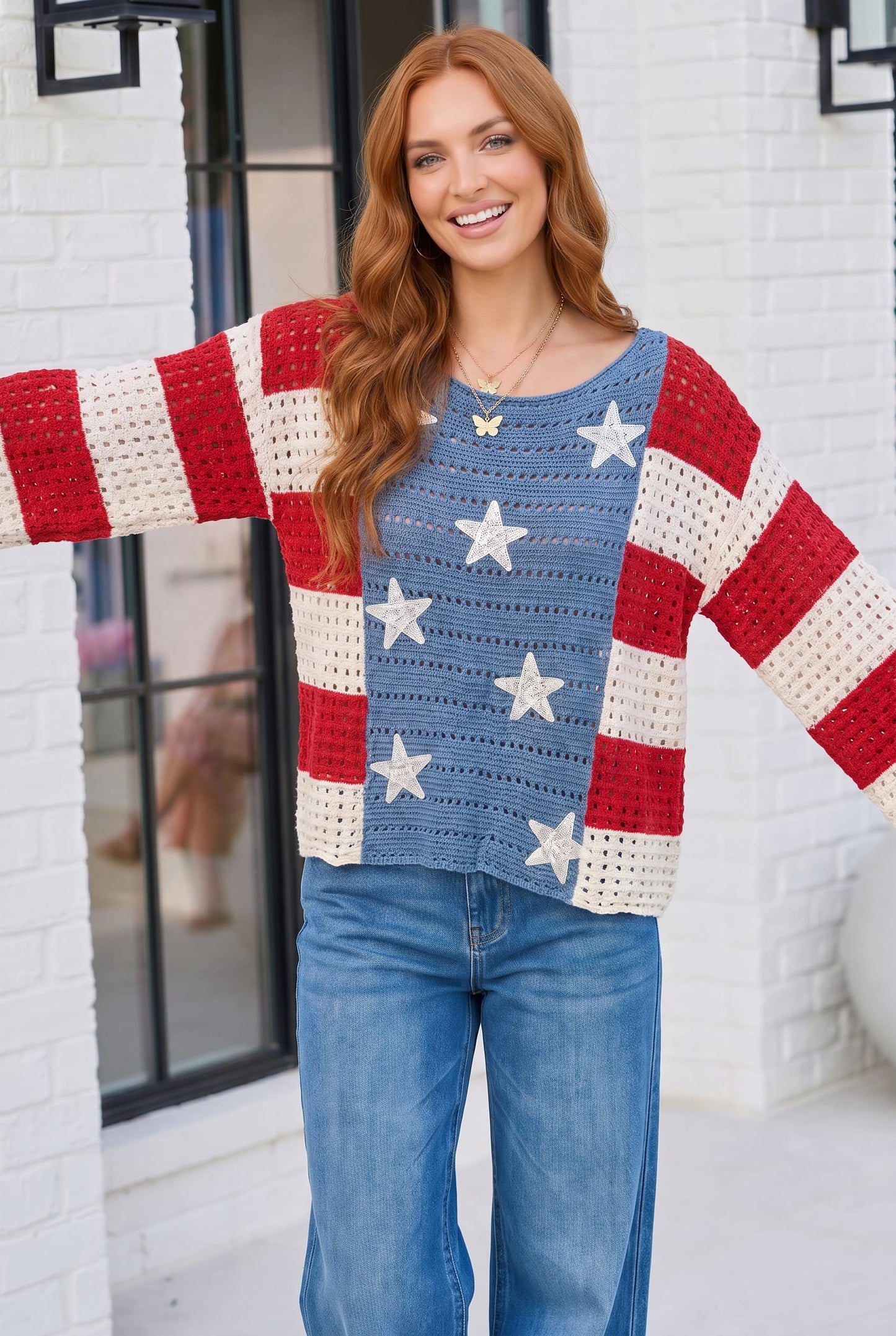 Woman wearing a colorful sweater with American flag design in front of a white building.