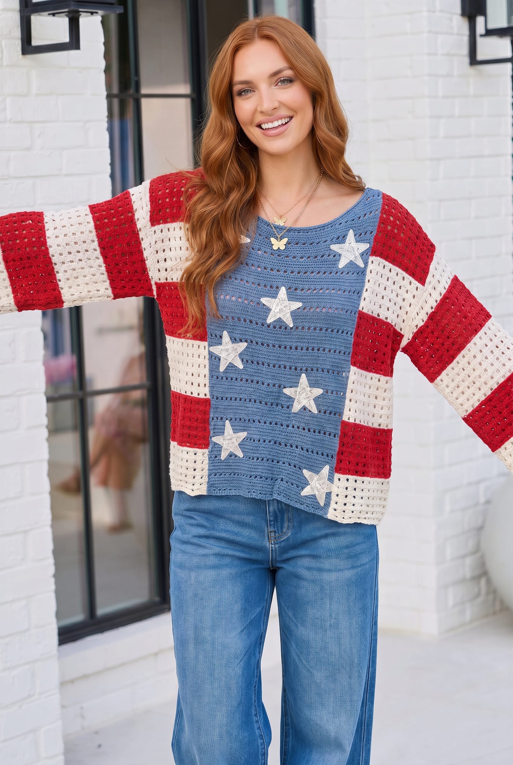 Woman wearing a colorful sweater with American flag design in front of a white building.