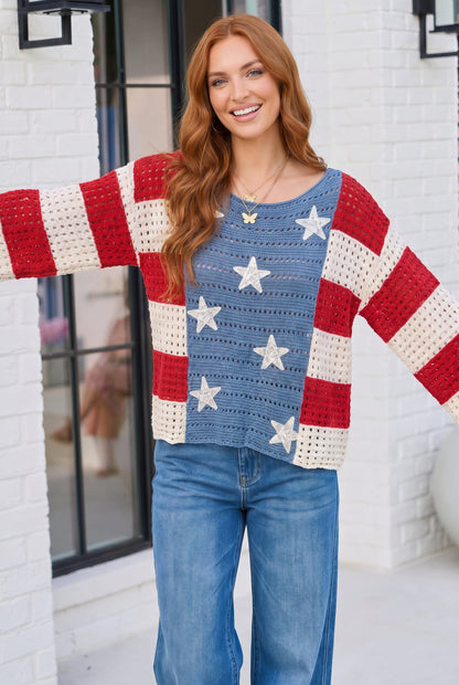 Woman wearing a colorful sweater with American flag design in front of a white building.