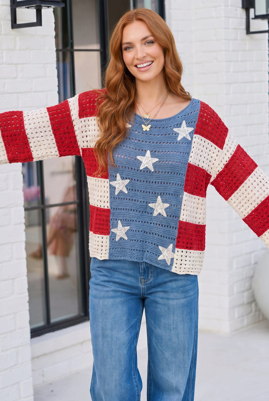 Woman wearing a colorful sweater with American flag design in front of a white building.