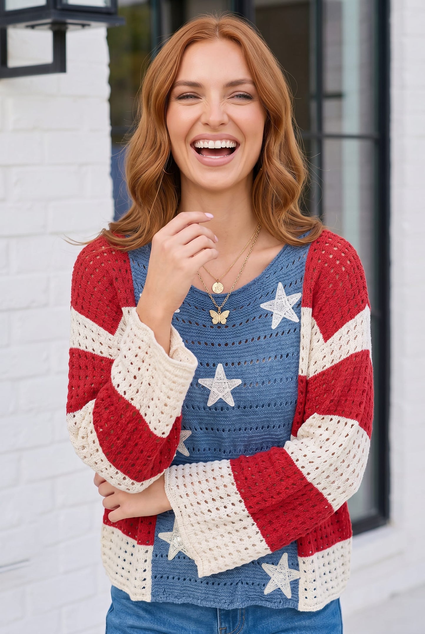 Woman wearing a colorful star-patterned sweater against a white brick wall.