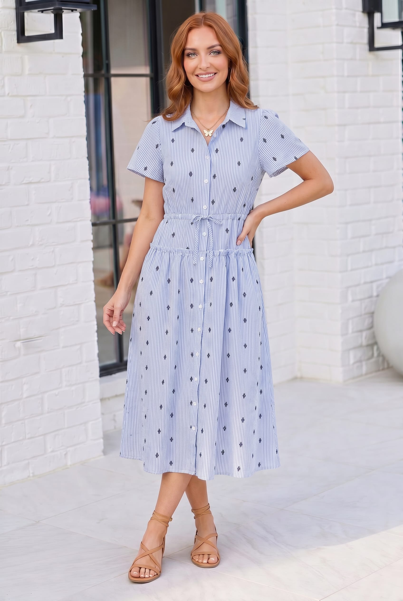 Woman wearing a light blue dress with a white brick wall background