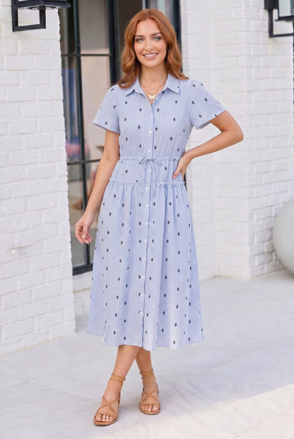 Woman wearing a light blue dress with a white brick wall background