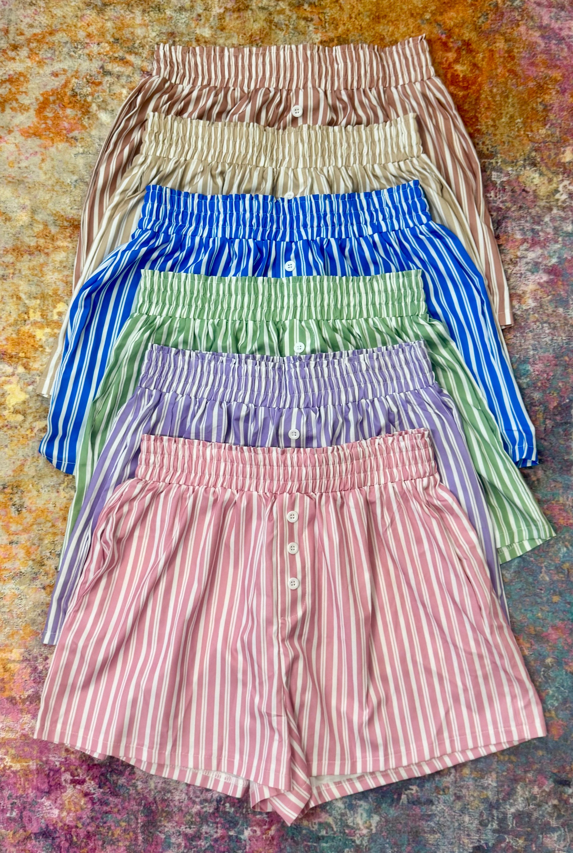 Stack of colorful striped shorts on a textured surface