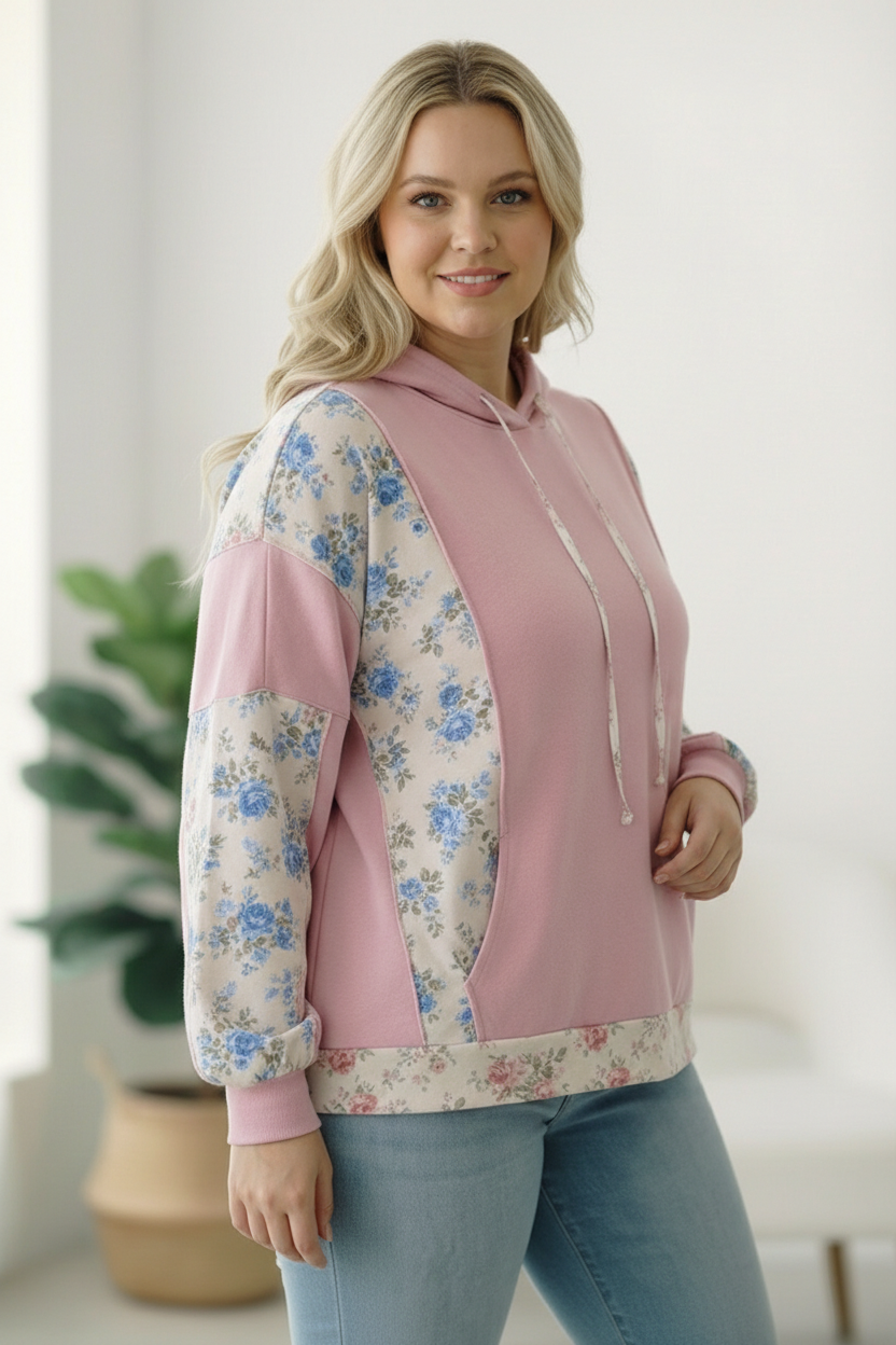 Woman wearing a pink hoodie with floral sleeves in a bright room.