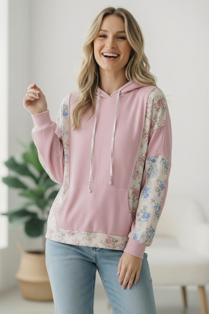 Woman wearing a pink hoodie with floral sleeves indoors
