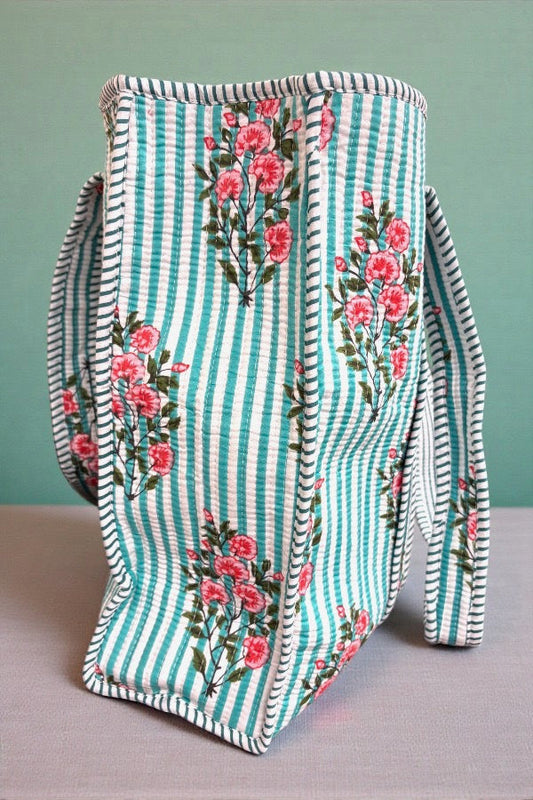 Fabric bag with floral pattern and striped design on a gray surface.