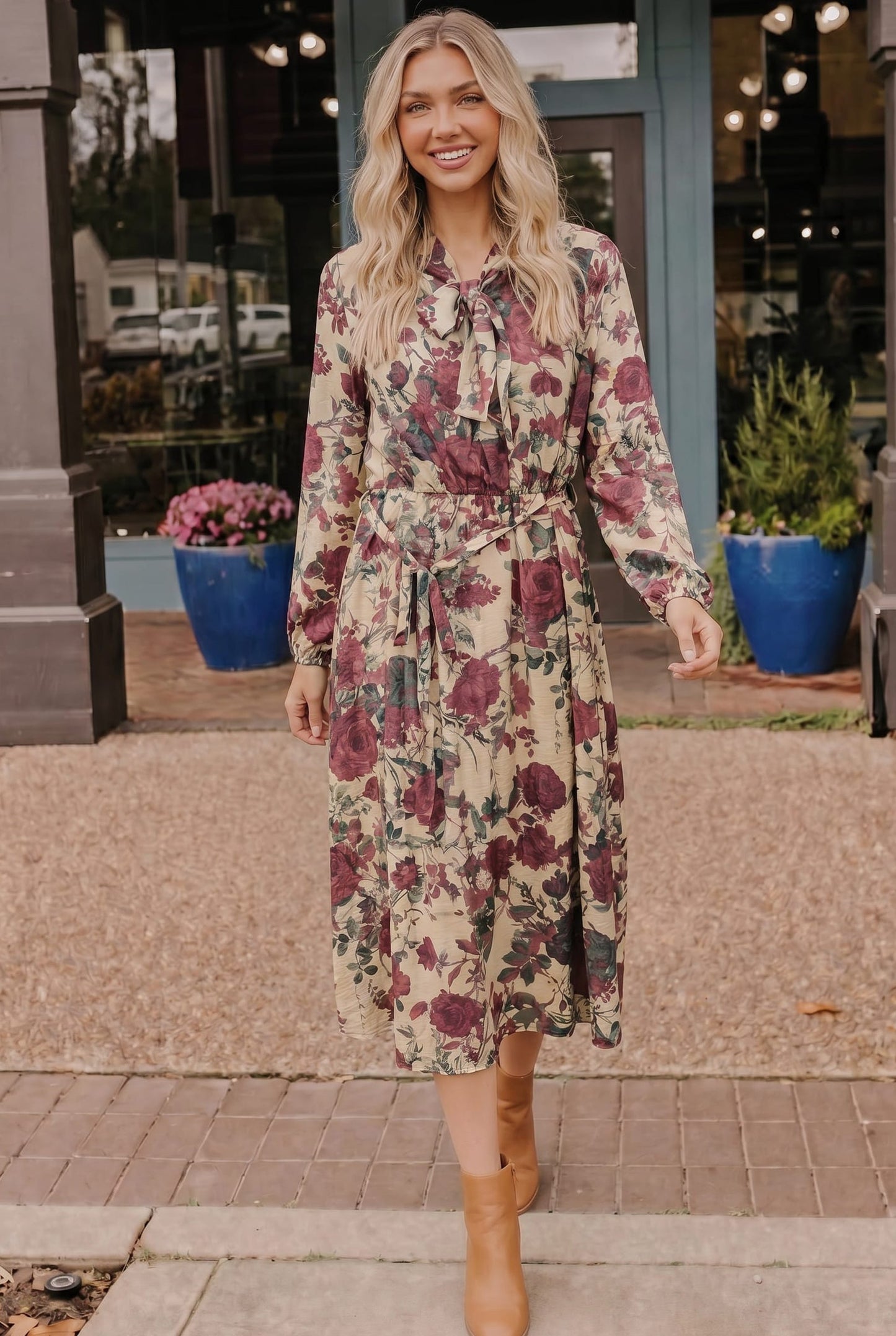 Woman wearing a floral dress standing outside a store.