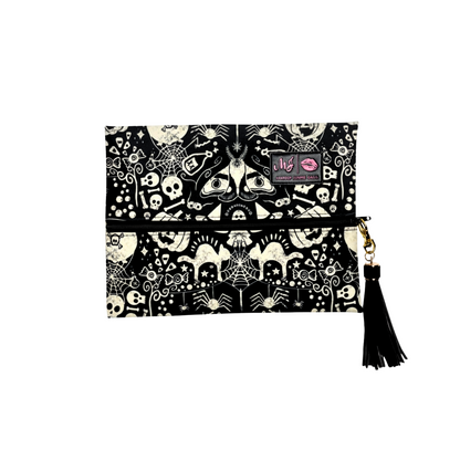 Clutch bag with Halloween-themed design featuring bats, skulls, and cobwebs on a white background.