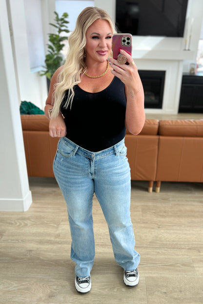 Women in black tank and High Rise V- Front straight Judy Blue jeans in a light wash color in a family room setting.